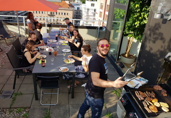 Das Seobility-Team sitz auf der Dachterrasse im Nürnberger Büro und grillt bei sonnigem Wetter.